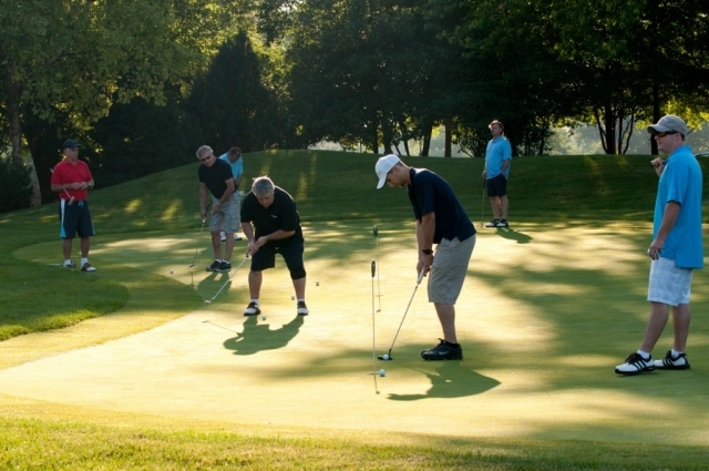 Golfers practicing putts at PowerForward DuPage golf outing at Bloomingdale Golf Club